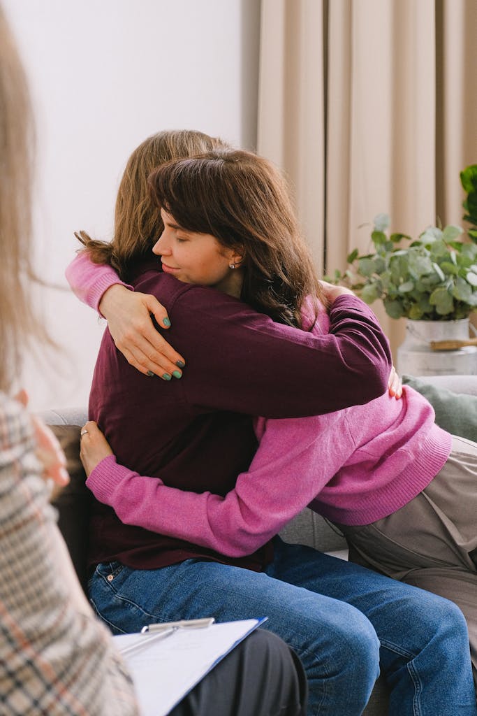 Friends hugging while sitting with coach in room